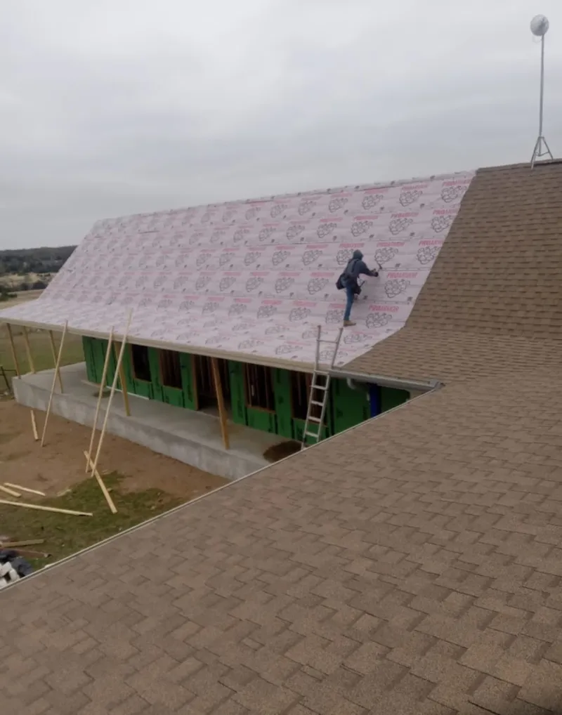 Worker preparing underlayment for a metal roof installation in St. Joseph
